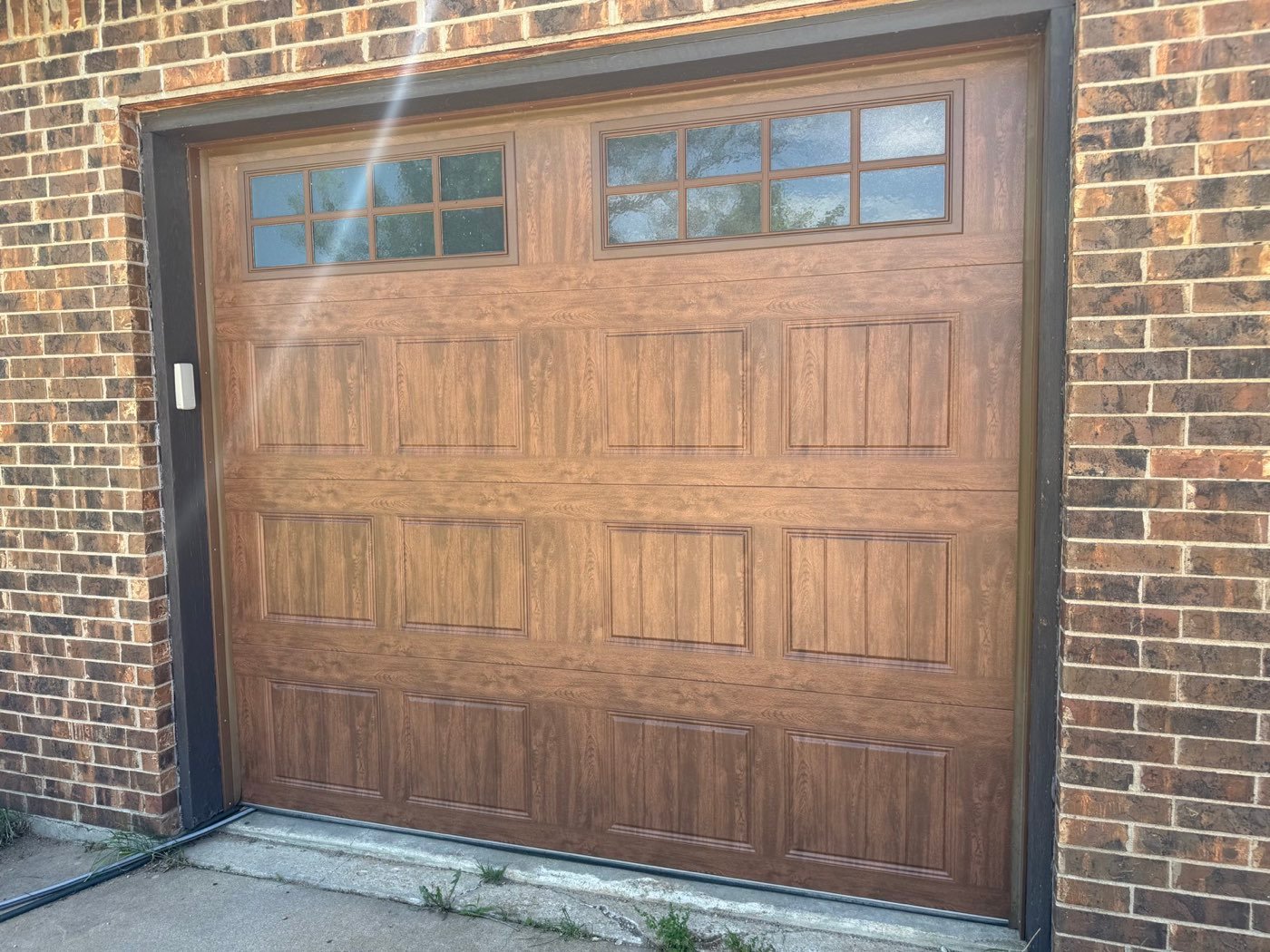 Brown carriage garage door with windows on a brick home