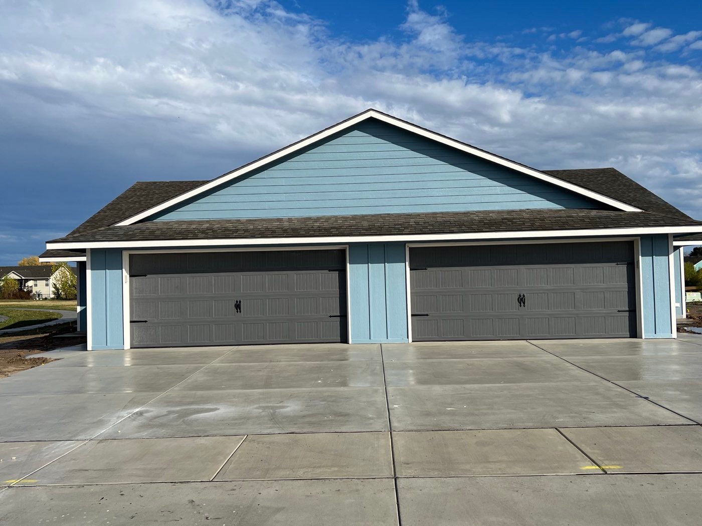 Two charcoal garage doors on a blue duplex