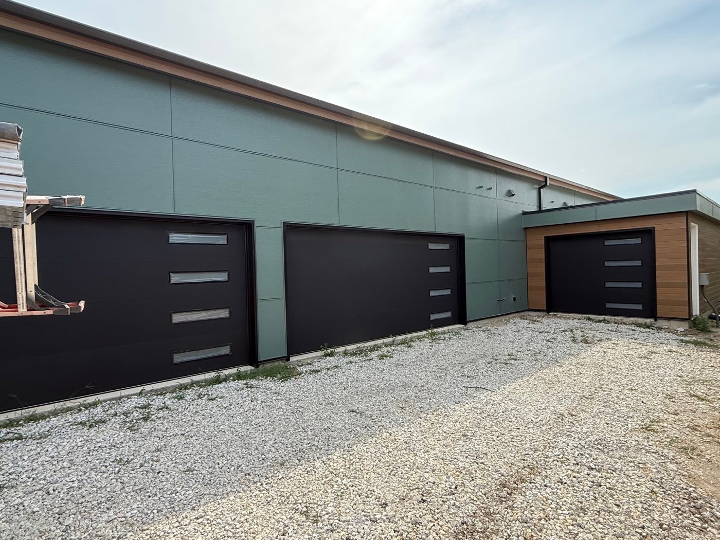 Three black modern overhead doors on a commercial building